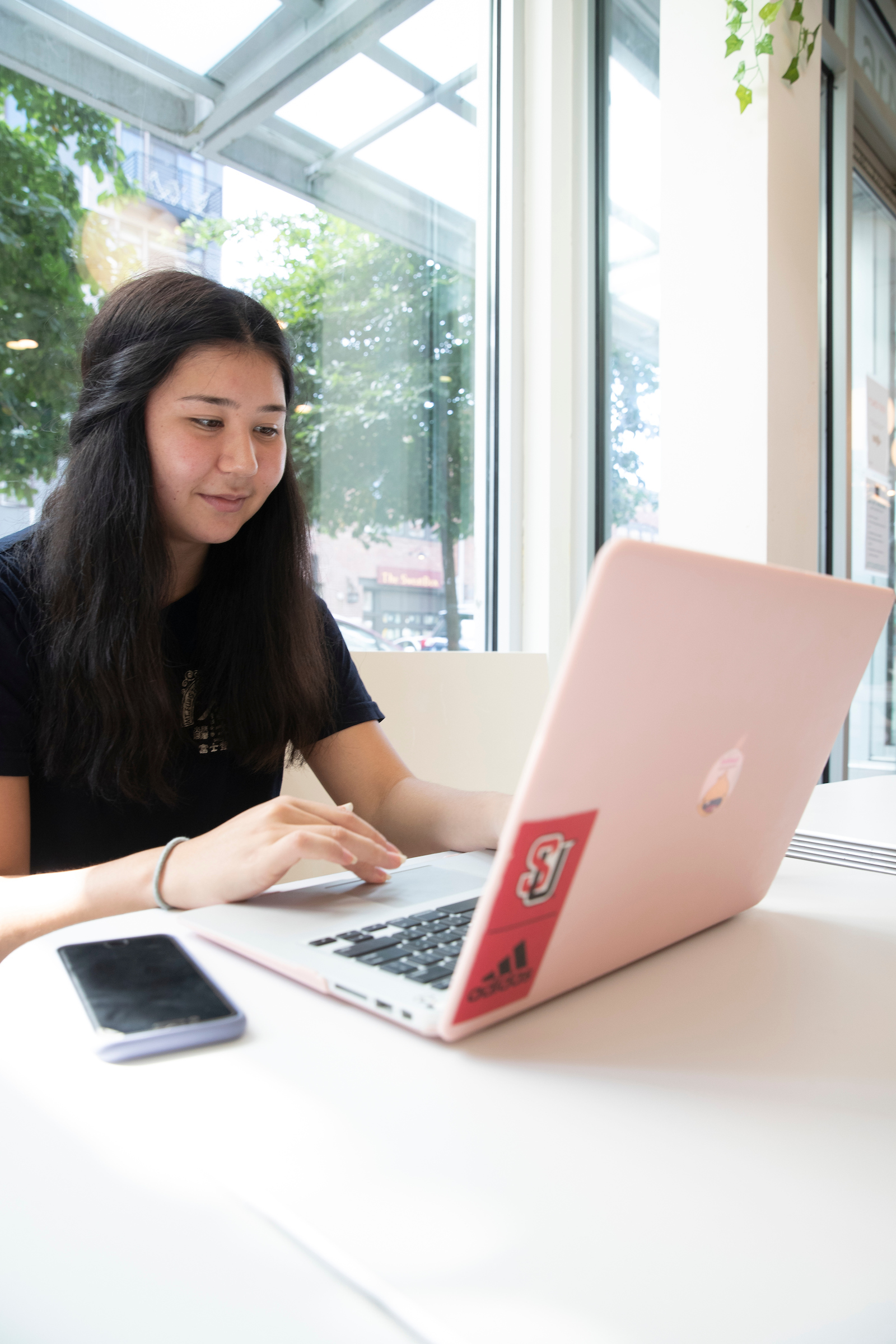 A student on a laptop with the Seattle University interlock logo